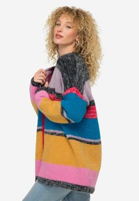 Färgglad, överdimensionerad cardigan i mjukt stickat material. Har horisontella ränder i rosa, gult, blått, lila och grått. Öppen framsida.