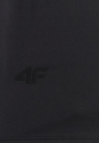 Tissu noir avec un subtil logo "4F" noir foncé imprimé près de la zone centrale inférieure.