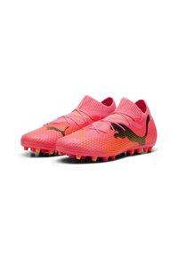 Botas de fútbol rosas con una parte superior texturizada, un cuello ajustado y una marca negra. La suela cuenta con tacos de colores brillantes para mayor tracción.