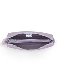 Lilac zippered wallet with dual compartments, smooth synthetic material, textured zipper, and a fuzzy pom-pom accent on the zipper pull.