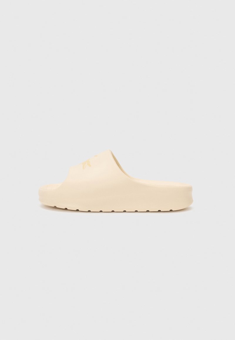 Lys beige slip-on sandaler laget av støpt gummi. Har en bred stropp og en teksturert såle med riller for bedre grep. Minimalistisk design.