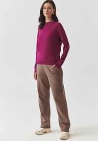 Roosa cashmere-sweater pikad varrukad, koos lahtiste beežide pükstega ja heledate sneakeritega. Lihtne disain, pehme tekstuur, mugav lõige.