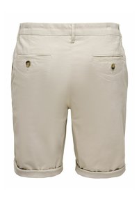 Shorts beige longueur genou avec revers roulés, poches à rabat boutonnées à l'arrière et passants de ceinture, vus de dos.