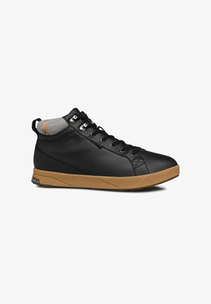 Zapatilla alta negra con parte superior de cuero sintético, cuello de textil gris, suela de goma y suela exterior de color marrón contrastante. Presenta ojetes de metal y detalles cosidos.