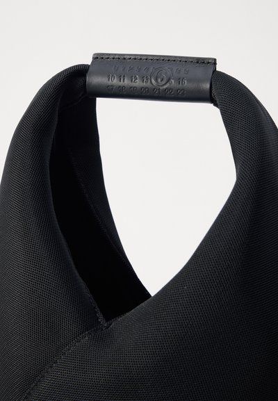 Μαύρη τσάντα tote από ύφασμα με υφή στην εξωτερική πλευρά και κυκλικό λουρί. Διαθέτει ανάγλυφους αριθμούς σε δερμάτινη λεπτομέρεια στο χερούλι.