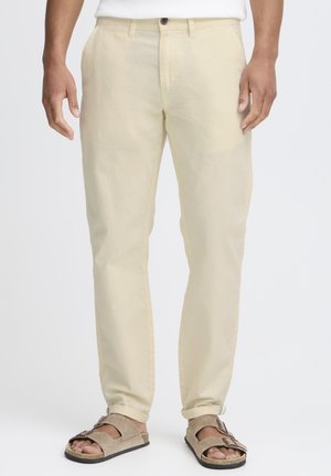 Beige chinos made of lightweight fabric, featuring a straight leg design, side pockets, and a single button closure at the waist.