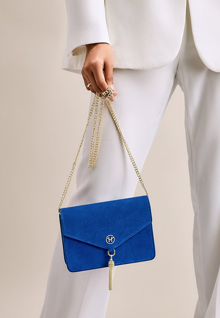 Borsa a tracolla in suede blu con catena dorata e dettaglio a frange, caratterizzata da un design a busta e un accento con logo rotondo.