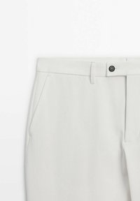 Pantaloni grigi chiari su misura con una texture liscia, dotati di due tasche laterali, passante per cintura e chiusura con bottone nero in vita.