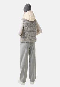 Szary kamizelka puchowa z kremowym kapturem, teksturowana tkanina i kwadratowy wzór, w połączeniu z jasnoszarymi spodniami i białymi trampkami.