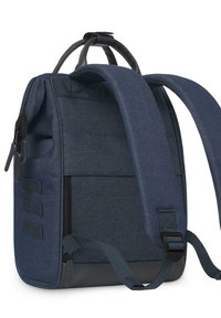 Sac à dos bleu marine avec un tissu texturé, deux poignées supérieures et des bretelles réglables. Il dispose d'un grand compartiment zippé et de poches latérales.