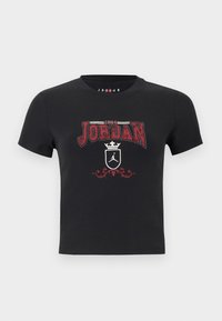 Μαύρο T-shirt με κοντά μανίκια, με κόκκινο κείμενο "1984 Jordan", λευκή κορώνα, ασπίδα με το λογότυπο Jumpman, και διακοσμητικό κόκκινο στολίδι από κάτω.
