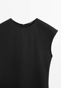 Sort ærmeløs top med rund halsudskæring og lynlås bagpå, lavet af glat stof, vist på en hvid baggrund.