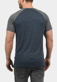 Short-sleeve t-shirt with navy blue body and gray raglan sleeves. Soft fabric, regular fit, with rounded hem and subtle stitching details.