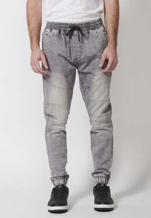 Pantaloni jogger din denim gri, cu talie elastică, șnur ajustabil și manșete cu nervuri. Prezintă o spălare estompată și mai multe detalii de cusătură.