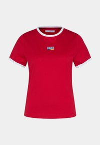 Camiseta de algodón roja con ribete blanco en el cuello y las mangas, que presenta un logotipo bordado rectangular en el pecho con acentos azules y amarillos.