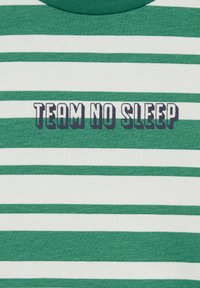 Zeleni in beli črtast majica s krožnim izrezom. Ima napis "TEAM NO SLEEP" v krepko črni in beli pisavi čez prsa.