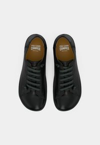 Musta nahkakengät pyöreällä kärjellä, vihreillä nauhoilla ja vaaleanruskealla sisävuorella. Kenkien sisäpohjassa on hienovaraiset ompeleet ja brändäys.