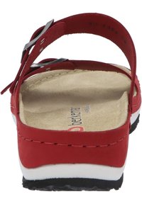 Red sandal with adjustable strap, flat sole, and cushioned insole. Features a smooth leather texture and a contrasting white midsole.