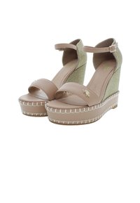 Béžové klínové sandály s páskem kolem kotníku, textilní svršek a hladká platforma; mají bílé švy a malý kovový detail.