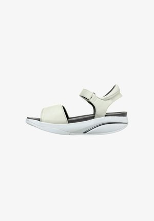 Sandal de cuero gris claro con una amplia correa para los dedos, correa ajustable para el tobillo y una suela acolchada que presenta un diseño curvado y un detalle mínimo.