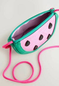 Borsetta a forma di anguria verde e rosa con chiusura a zip, dettagli neri lucidi a forma di seme e tracolla rosa rimovibile. L'interno è a quadretti rosa.
