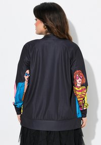 Zwarte bomberjack met kleurrijke cartoongraphics op de mouwen. Heeft ribgebreide manchetten en tailleband, een gladde textuur en een comfortabele pasvorm.