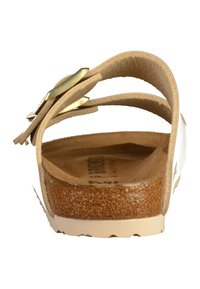 Sandalo bianco con più fascette beige e dettagli dorati, dotato di una soletta in sughero e una suola leggera e testurizzata.