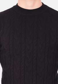 Maglione nero lavorato a maglia con un design a trecce testurizzato, scollo rotondo a costine e maniche lunghe. Materiale morbido con una vestibilità aderente.