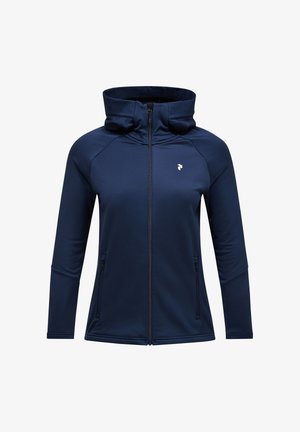 Tume sinine tõmblukuga jakk, mis on valmistatud pehmest ja venivast kangast. Omab kõrget kaelust, pikki varrukaid ja kahte küljetaskut. Üksik kerge disain.