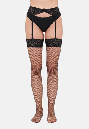Calze autoreggenti in rete nera con bordo in pizzo, cinghie per reggicalze e culotte. Il motivo a rete copre le gambe, mentre il pizzo aggiunge texture al bordo superiore.