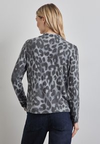 Harmaa leopardi-kuosisweater pitkillä hihoilla, pehmeästä materiaalista ja pyöreällä kaula-aukolla. Mustat ja vaaleanharmaat kuviot, rento istuvuus.
