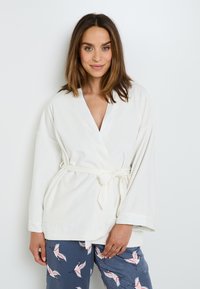 Robe bianca avvolgente con maniche larghe e cintura; stoffa morbida; abbinato a pantaloni blu navy con un motivo di uccelli. Tessuto liscio, design casual.