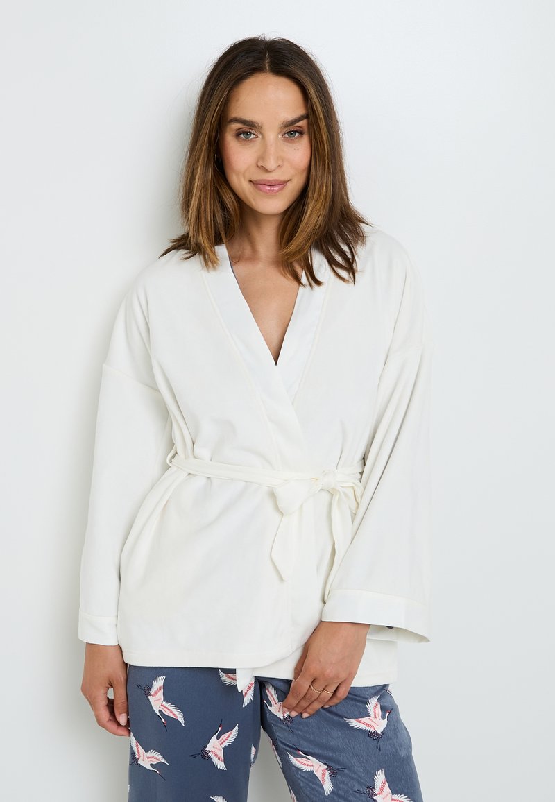 Robe bianca avvolgente con maniche larghe e cintura; stoffa morbida; abbinato a pantaloni blu navy con un motivo di uccelli. Tessuto liscio, design casual.