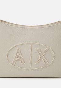 Borsa a mano in pelle texturizzata color crema con forma arrotondata, dotata di lettering "A|X" in rilievo contornato da piccole perline. Fodera interna liscia.
