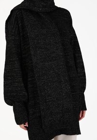 Black knit oversized sweater featuring a high collar, textured pattern, and ribbed cuffs, with metallic thread accents throughout.