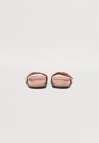 Rosa gummisandaler med flat såle, med en enkelt stropp og en liten gullkjedeakcent. Glatt tekstur, minimalistisch design.