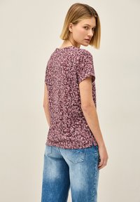 Haut à manches courtes, maroon et blanc à motifs avec un col rond, texture douce et coupe décontractée, associé à un jean en denim bleu clair.