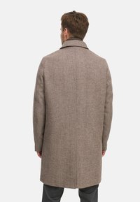 Bruine wollen mix jas met een gestructureerde kraag, rechte snit en lange mouwen. Beschikt over een achternaad en textuurstof.