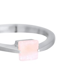Srebrna narukvica glatkog, zaobljenog dizajna sa četvrtastim, svijetloružičastim kamenom u sredini, koji pokazuje blagu prozirnost i teksturu.