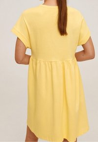 Vestido amarillo de algodón con mangas cortas y cintura fruncida. La tela parece suave con una textura lisa y un ajuste relajado.