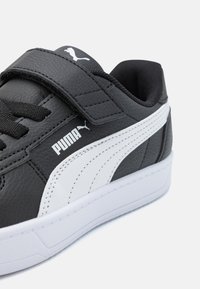 Baskets en cuir noir avec accents blancs, finition texturée, strap Velcro et logo PUMA. Semelle blanche épaisse et design sportif classique.