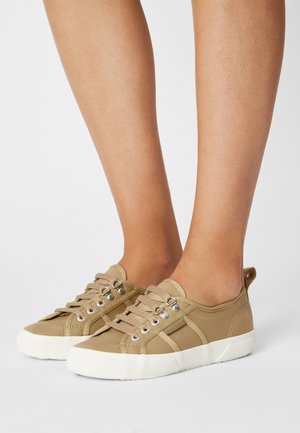 Baskets en toile beige avec une semelle en caoutchouc texturée, dotées d'œillets argentés, d'un bout arrondi et d'une languette arrière pour un enfilage facile.