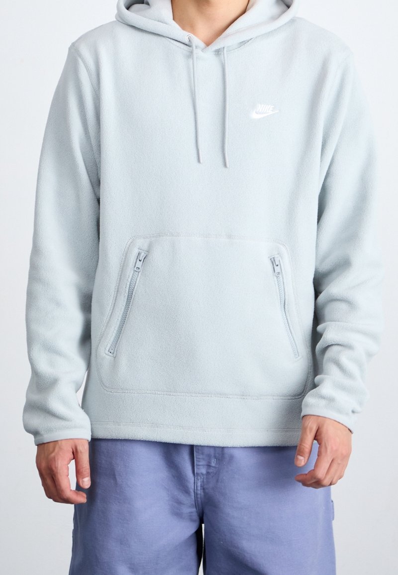 Ljusblå fleece-hoodie med dragsko på huvan, känguruficka och med dragkedja i sidofickorna. Logotyp på bröstet. Mjuk textur och avslappnad passform.