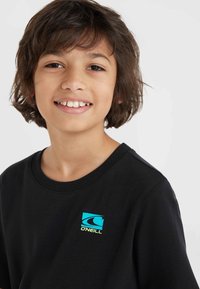 Camiseta de algodón de manga corta en negro, con un logo de O'Neill en azul y amarillo en el lado izquierdo del pecho. Textura suave, corte clásico.