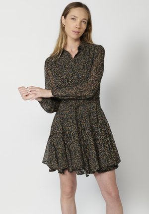 Robe florale noire avec manches longues, col et jupe évasée. Présente des motifs floraux multicolores et un détail de taille froncé.