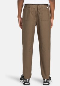 Brown, lightweight pants with a relaxed fit, elastic waistband, and two back pockets. The fabric has a subtle texture.