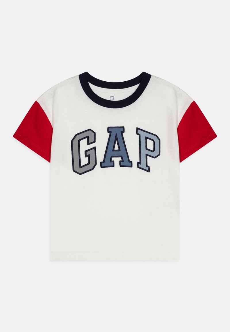 White t-shirt with navy crew neck, red sleeves, and embroidered "GAP" logo in blue and gray. Soft cotton material, short-sleeved design.