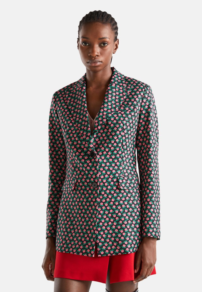 Blazer imprimé en noir, avec un motif floral aux accents roses et verts, conception à boutonnage simple et revers crantés. Coupe slim.