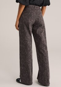 Pantalones de pierna ancha en marrón oscuro con un estampado de leopardo, que presentan una textura suave, cintura alta y bolsillos traseros.