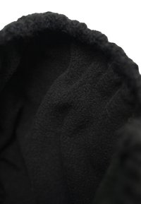 Black fleece interior of a hat, featuring a soft texture and curled edge. The material appears warm and thick, designed for comfort.